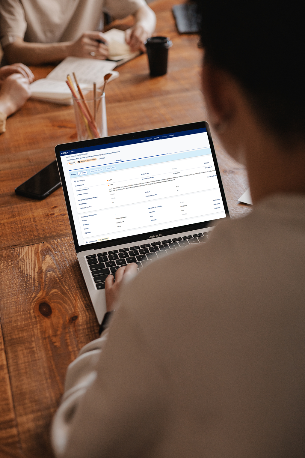 photo of a user taken from the back, he is sitting on wood desk and using INCA app on laptop